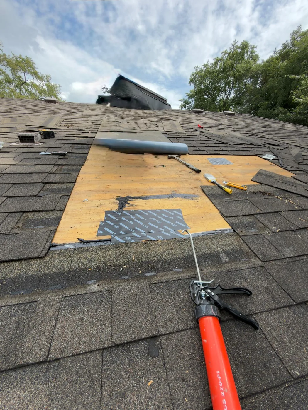 The repaired deck area with underlayment being set and a sealant gun in the foreground.