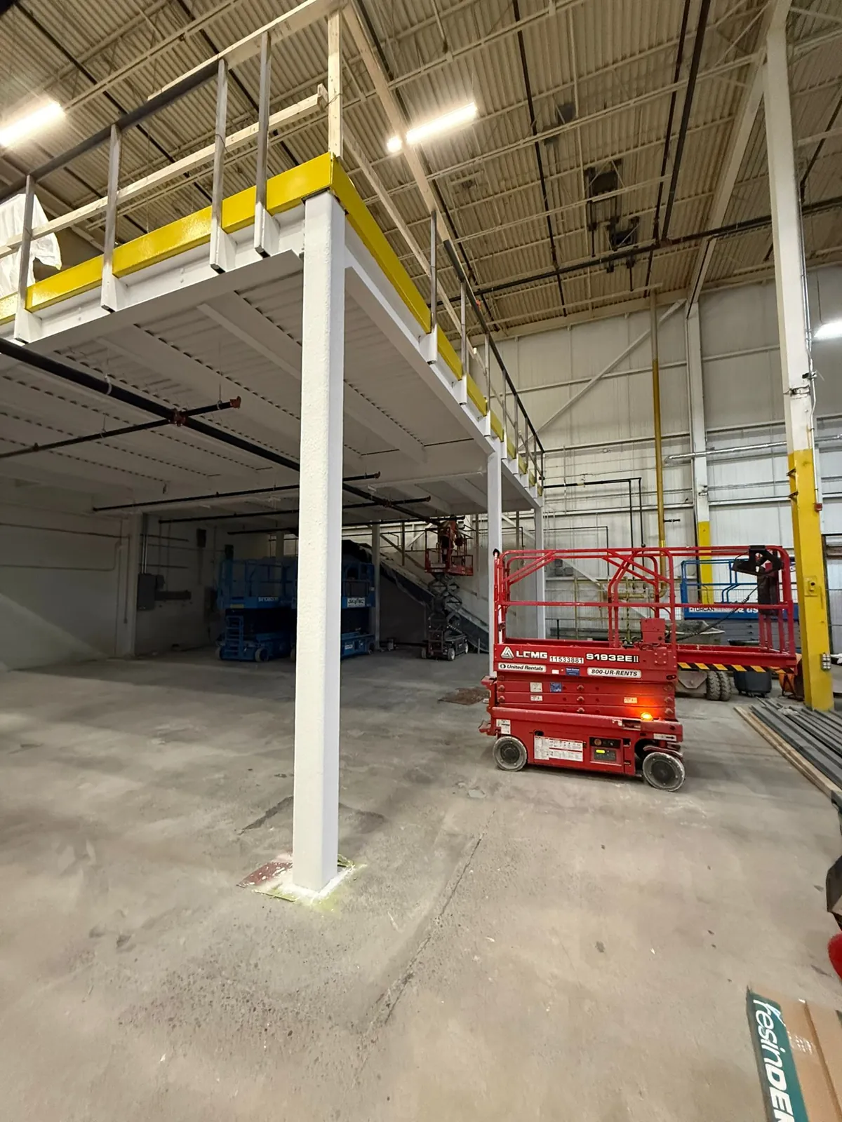 Mezzanine columns, beams and deck underside coated in white intumescent fireproofing