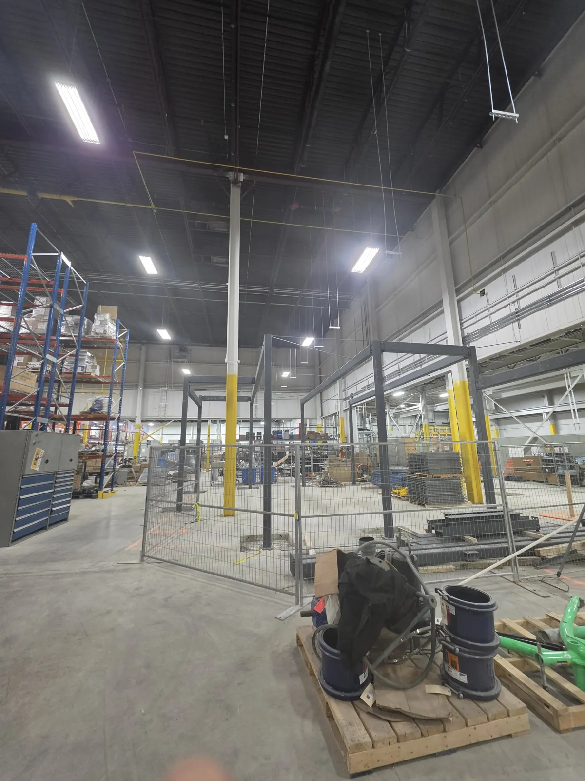 Before: bare dark steel frames inside a fenced work area in the operating warehouse